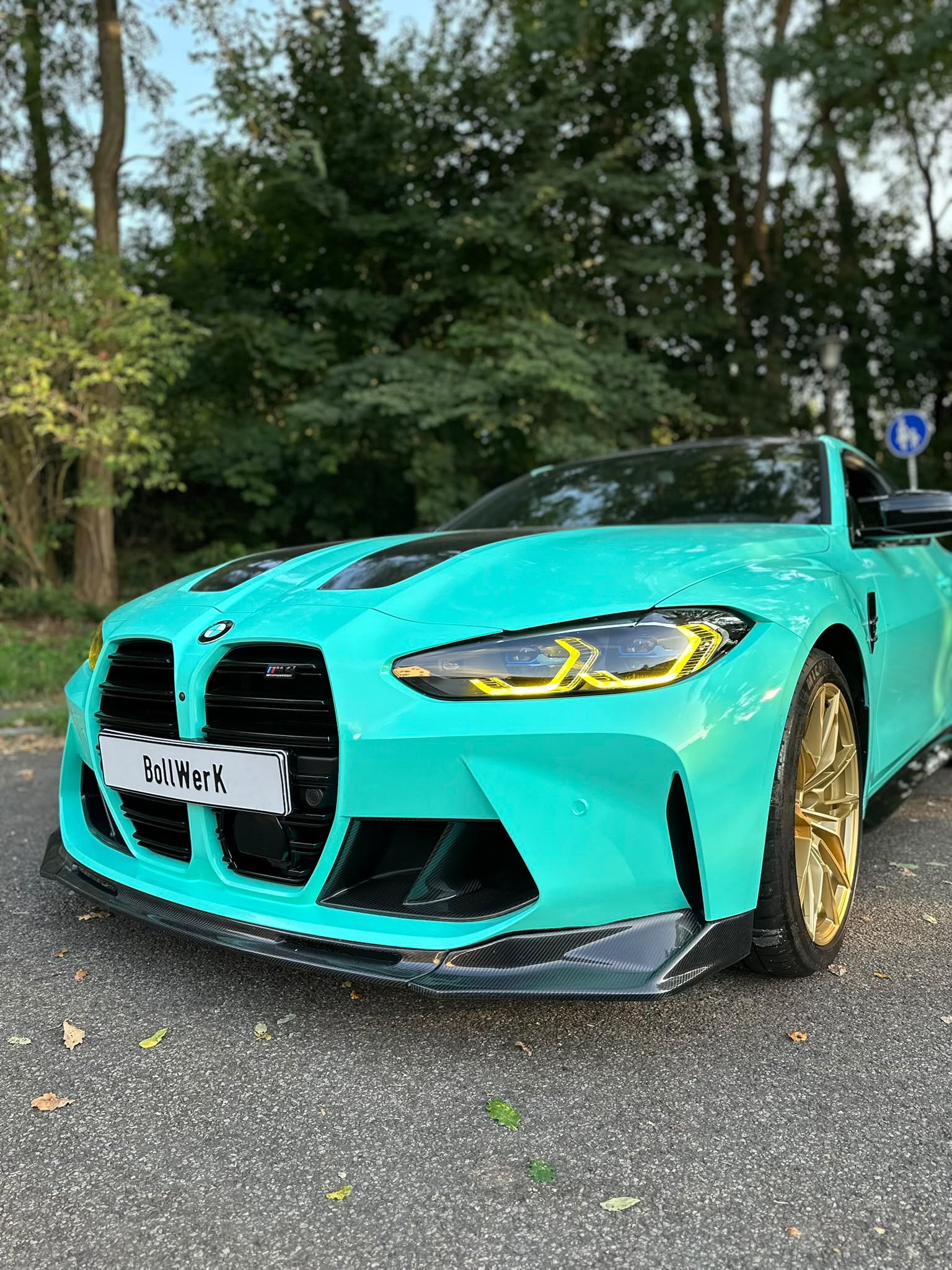 Türkisfarbener BMW mit sichtbarer Front und gelben Lichtakzenten