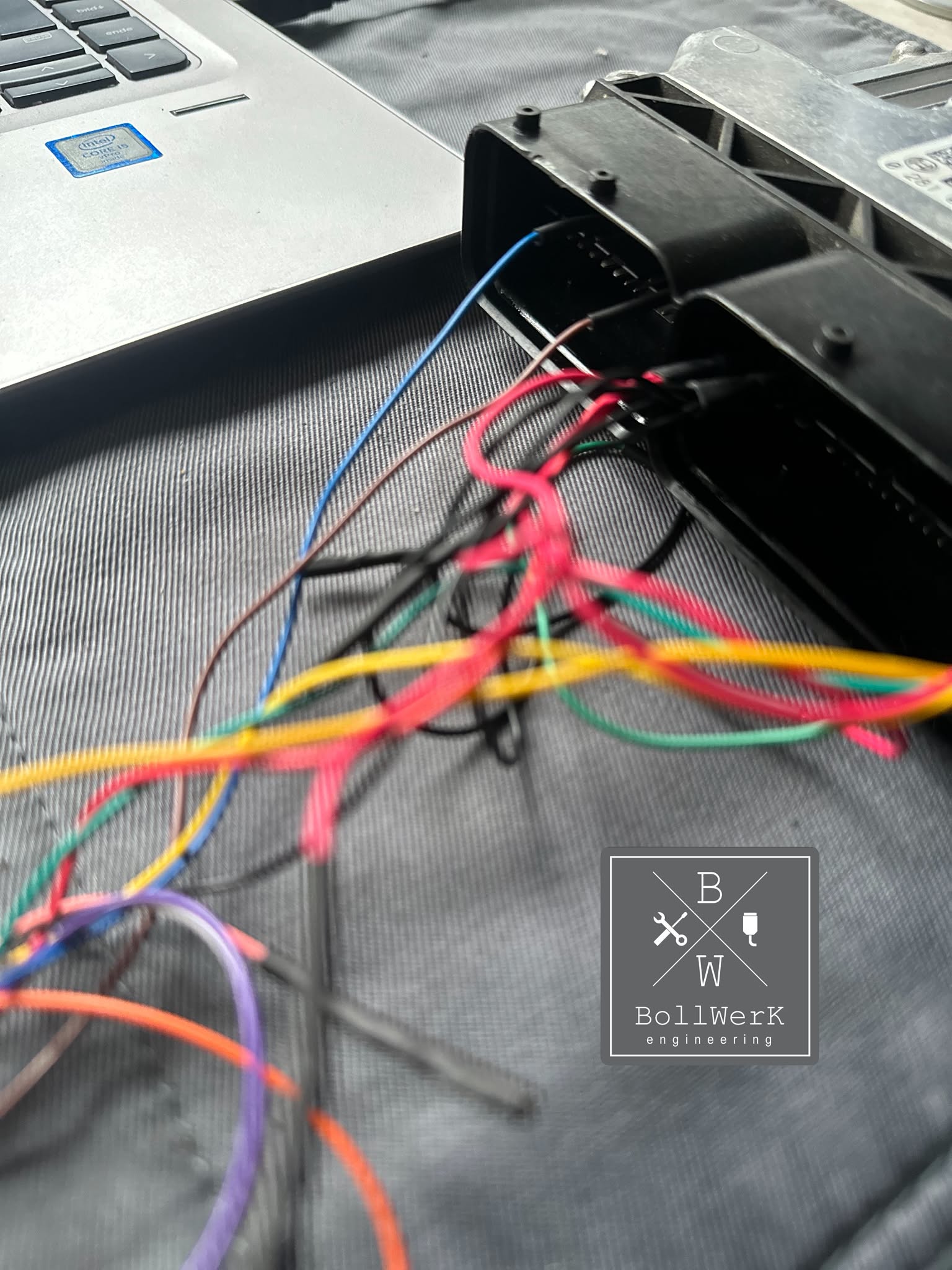 Steuergerät mit angeschlossenen Leitungen neben einem Laptop